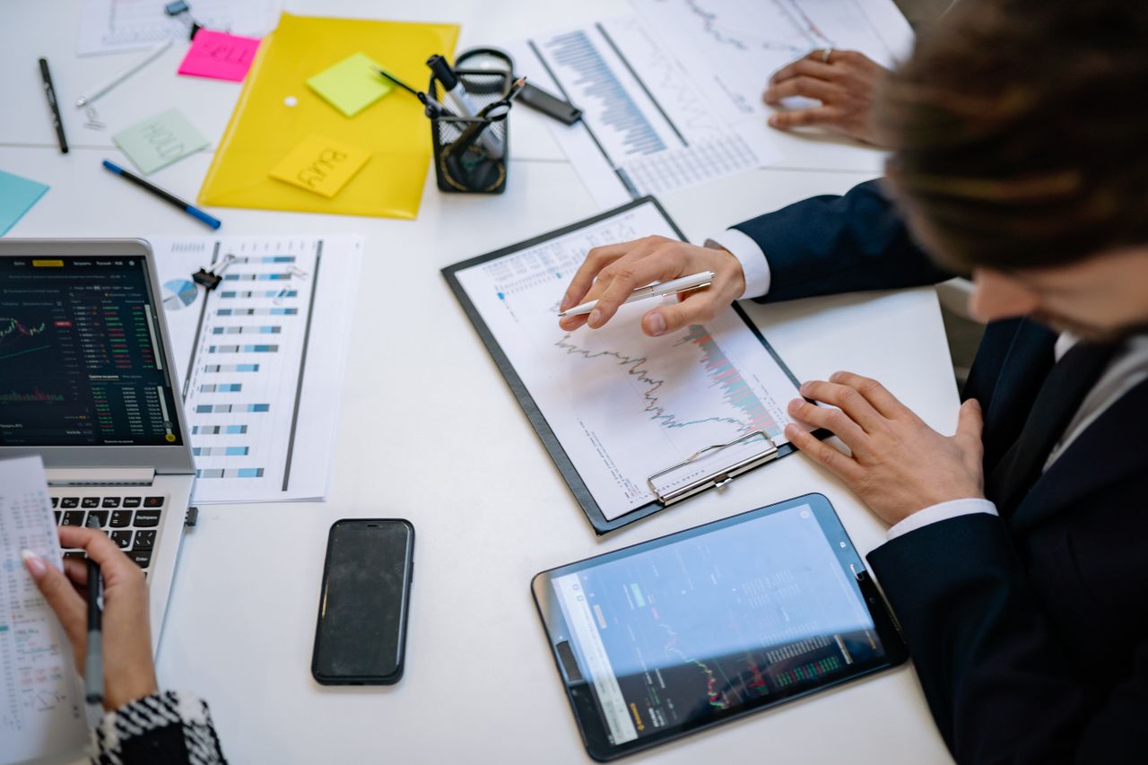 A team analyzes financial charts and digital data on tablets in an office environment.